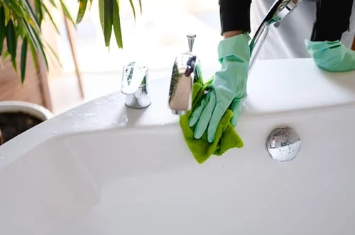Bathroom basin and fixtures being cleaned by hand
